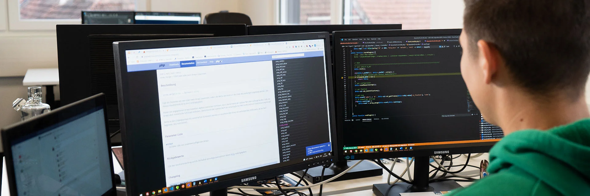 Mann beim programmieren vor Bildschirmen