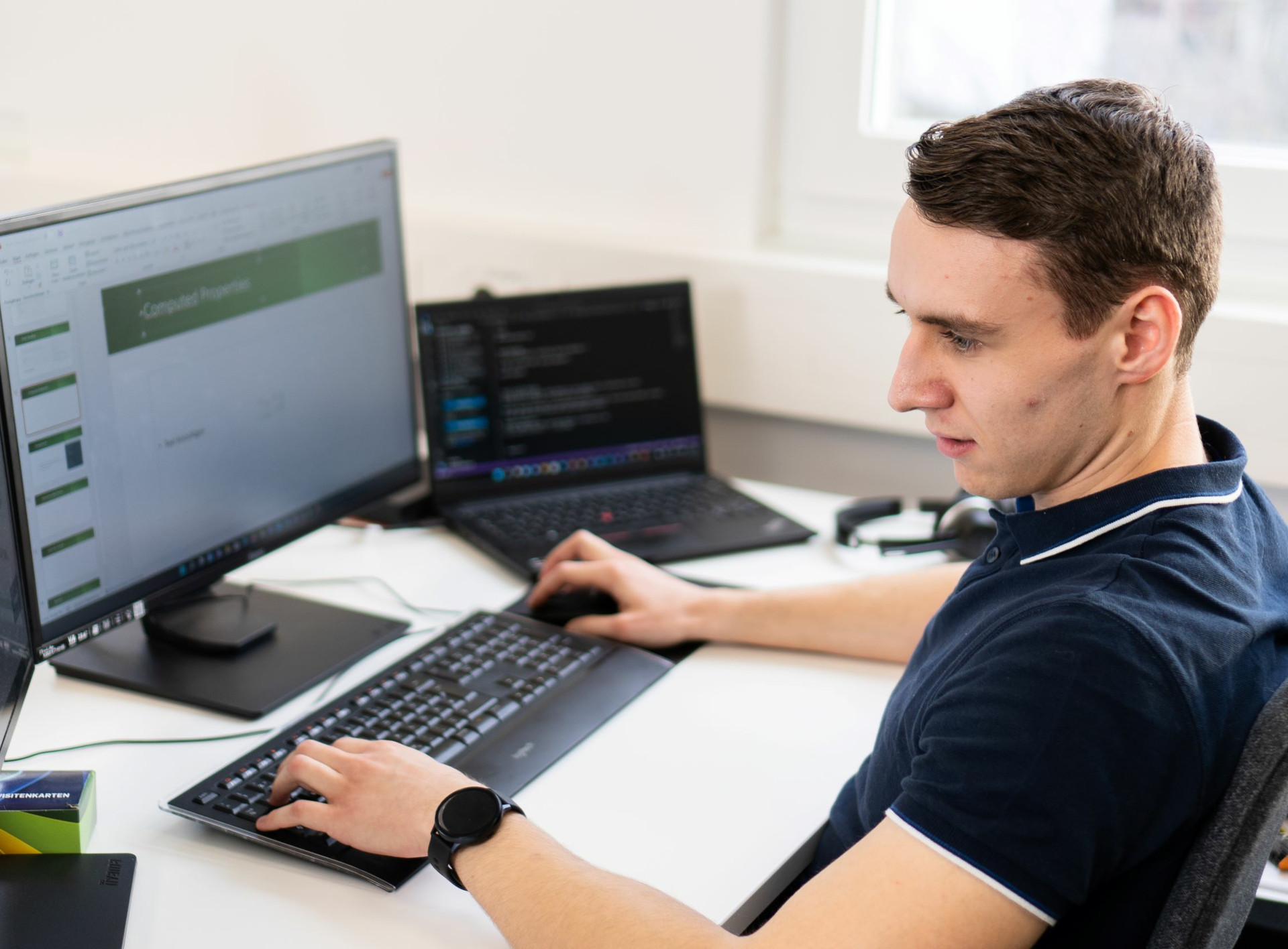 Mann sitzt vor Bildschirmen und programmiert